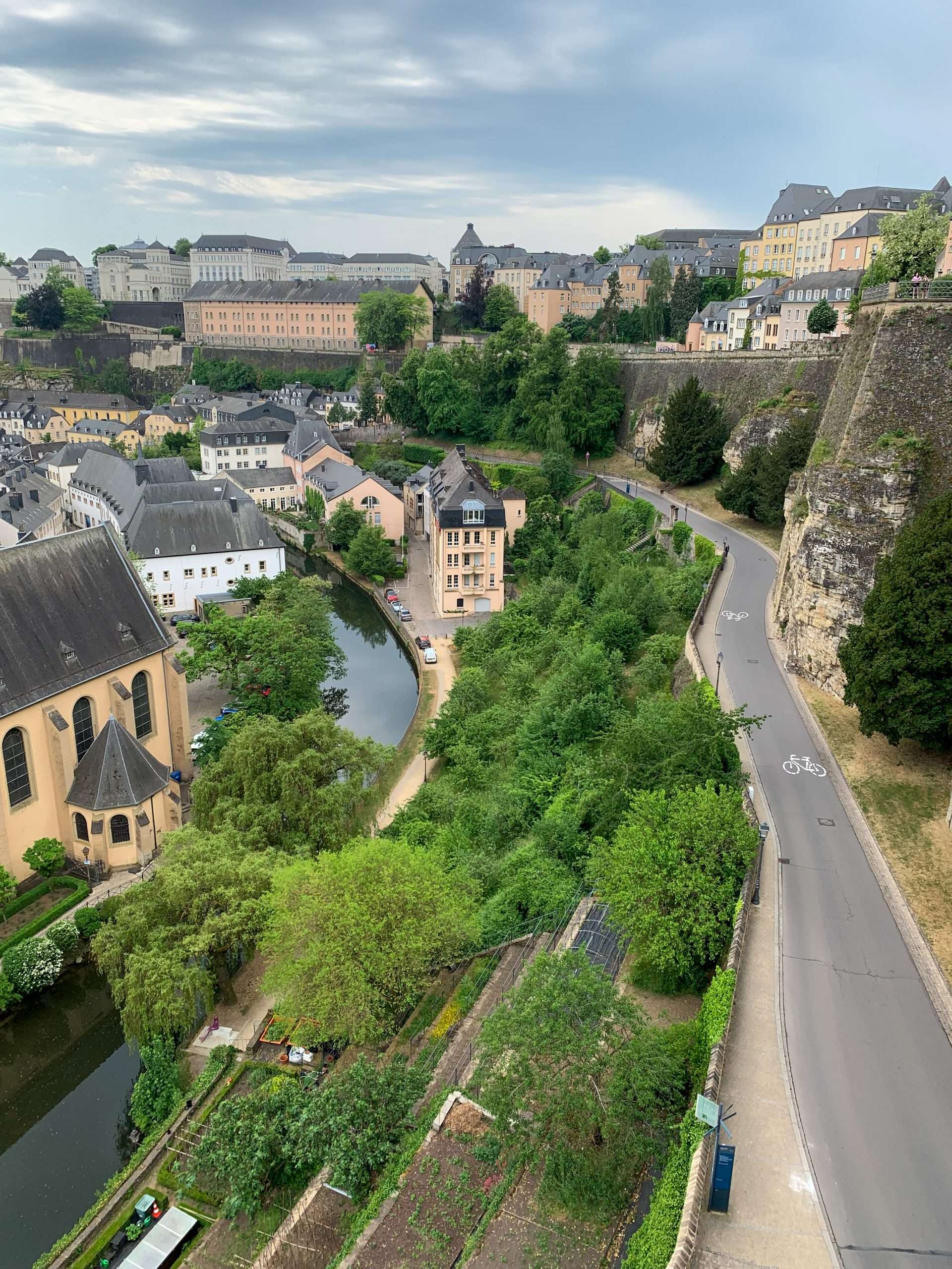 A view overlooking the Corniche in Luxembourg with much greenery visible along with the river and surrounding buildings.
