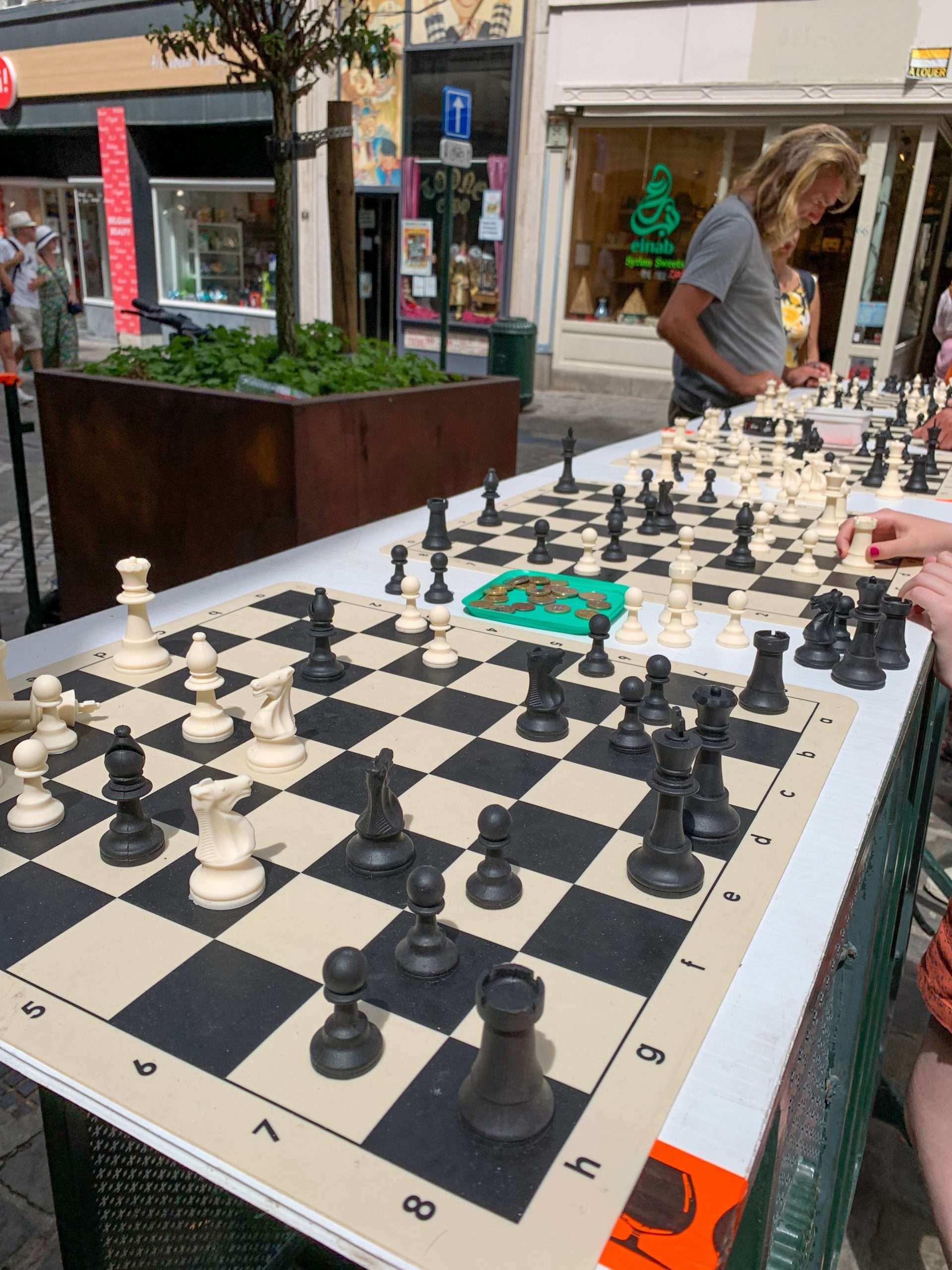 Image shows a street scene where multiple chess games being played in Brussels 