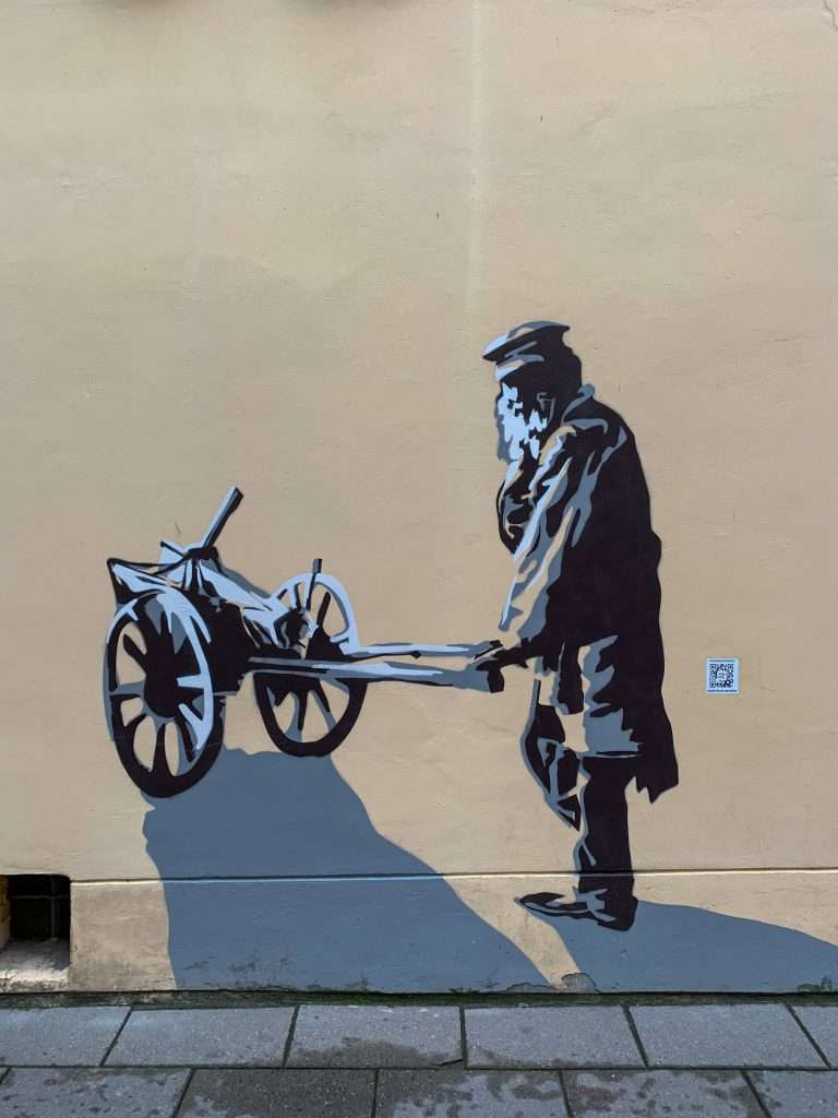 Image shows street art in the Jewish Quarter of Vilnius. The art depicts a Jewish man with a wheel barrow who resided in Vilnius old town before WW2