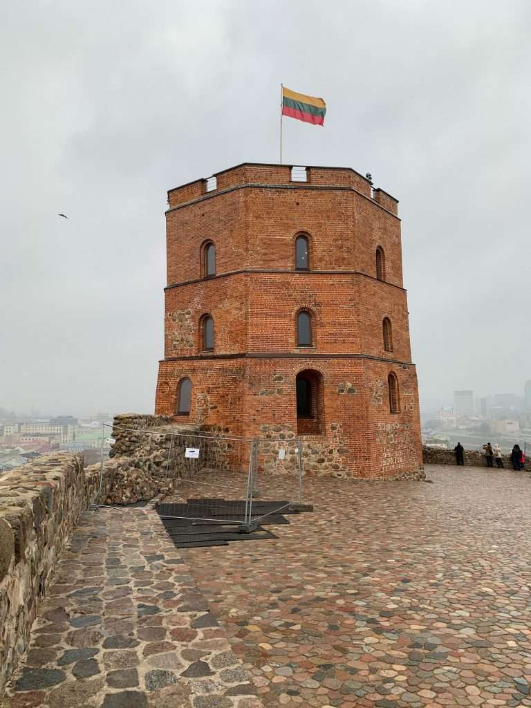 Image shows Gediminas Castle Tower in Vilnius with the Lithuanian flag flying from its top.