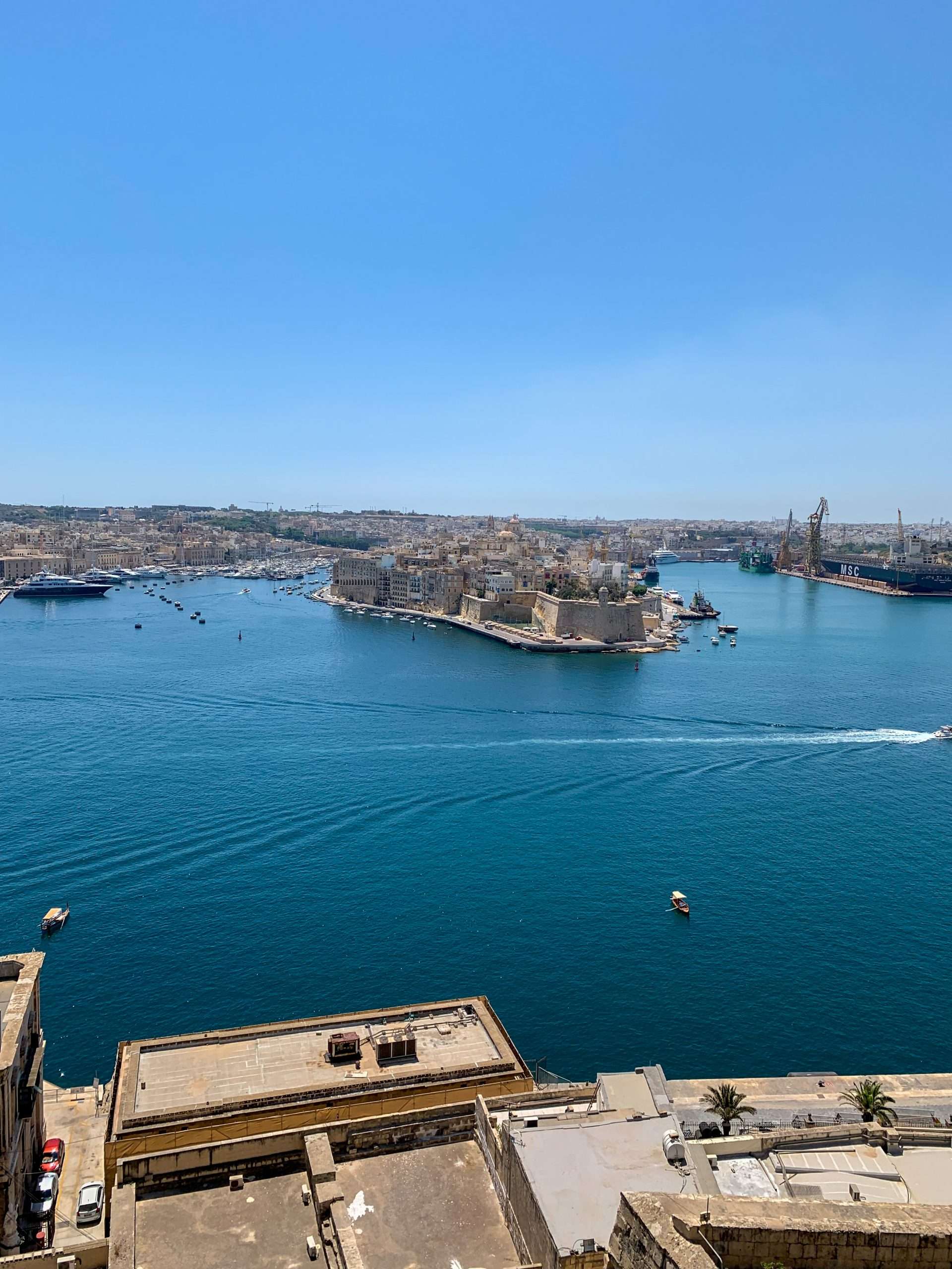 A panoramic view over the Grand Harbour in Malta with a calm sea and a few boats visible. 