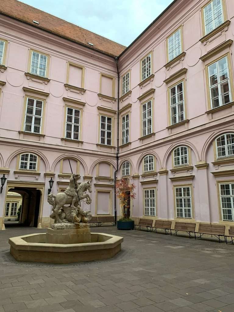 A water fountain, without water, stands in the inner courtyard of the pink coloured Primate Palace in Bratislava. A statue of St George forms part of the fountain.