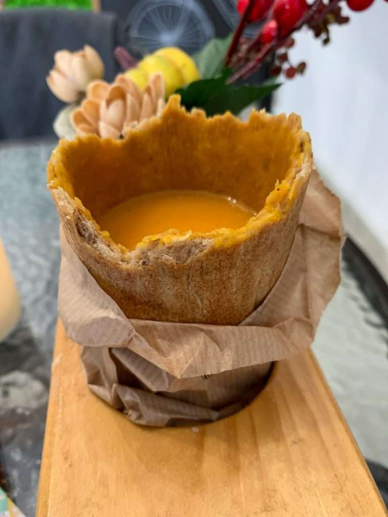 Image shows soup in an edible cup purchased from Soup Culture in Bratislava, with only a little over half of the edible cup remaining!