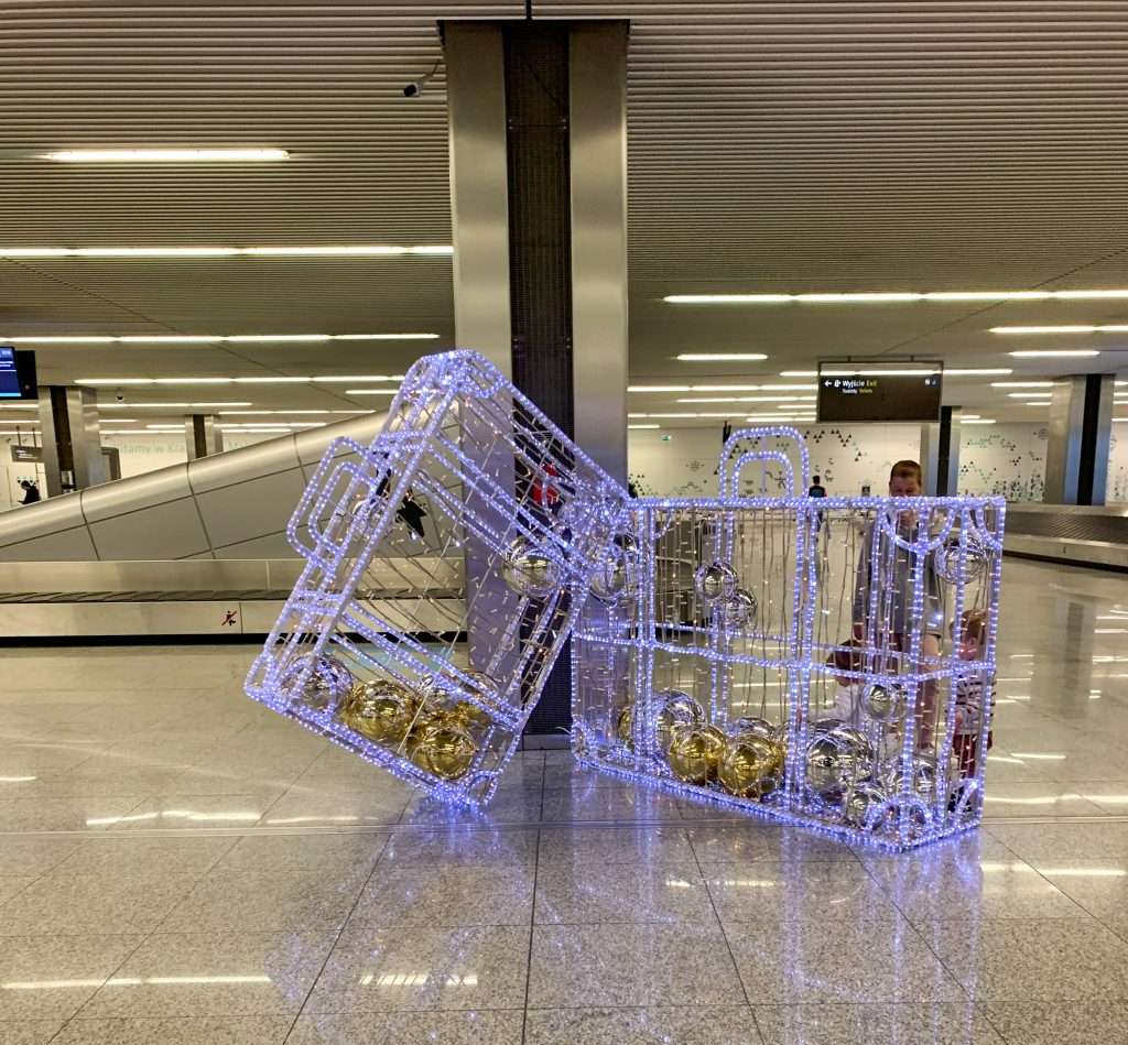Image shows some illuminated suitcases at Krakow airport. They are decorated with Christmas lights as the image was captured in December 2022