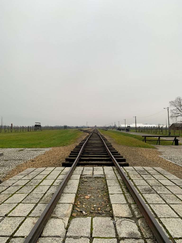 Image shows the view looking along the train tracks toward the entrance of Auschwitz II