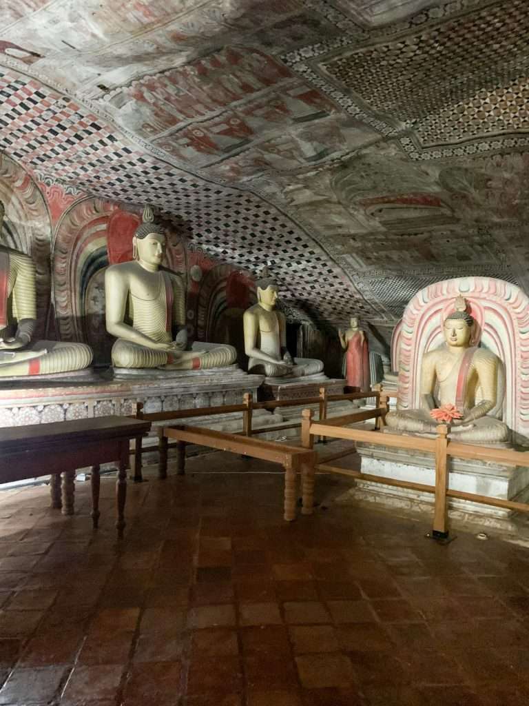 Image shows various statues of Buddha within the Dambulla Cave complex.