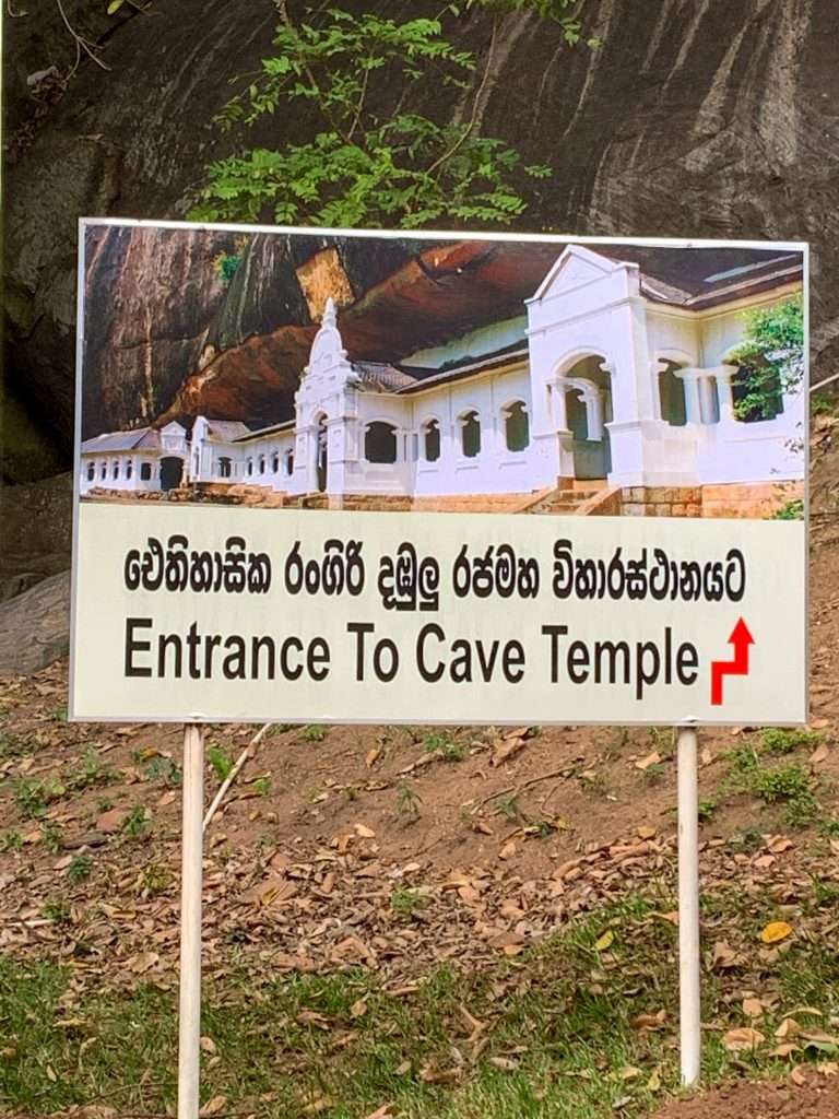 Image shows a sign indicating the way to the entrance for the Dambulla Cave complex, one of the best things to see in Sri Lanka 
