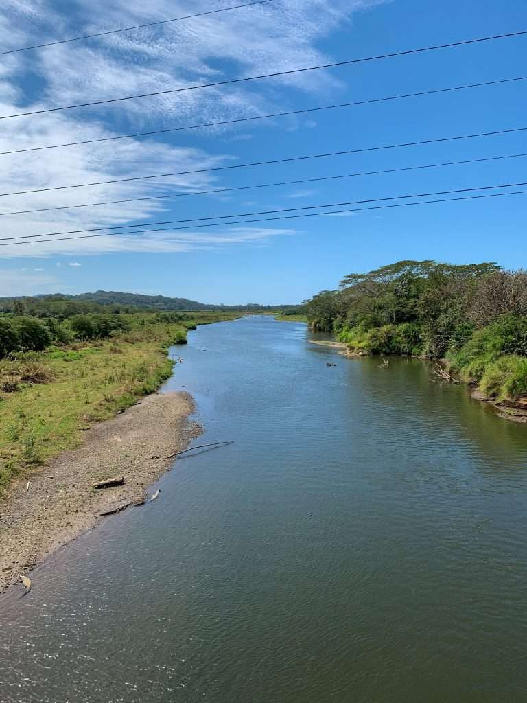 Image shows a view of the Tarcoles River, Costa Rica home to many American crocodiles and a must stop on any Costa Rican road trip!