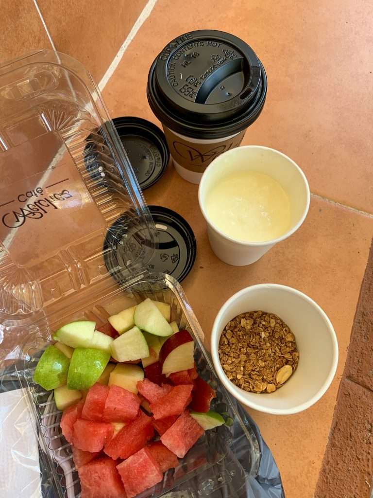 A breakfast on the go in Copan, Honduras. Muesli, fresh fruit (apples and melon) and coffee are visible. 