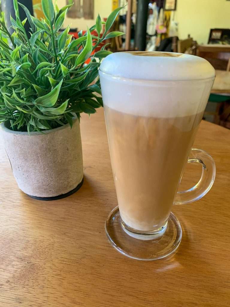The view inside a the Casa de la Abuela with a close up of a latte and a small green plant as table decoration.