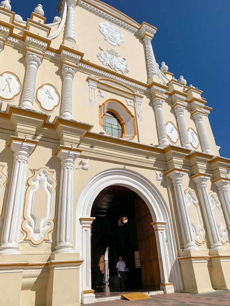 Image shows the La Merced church, a creamy white and lemon coloured church in León Nicaragua.