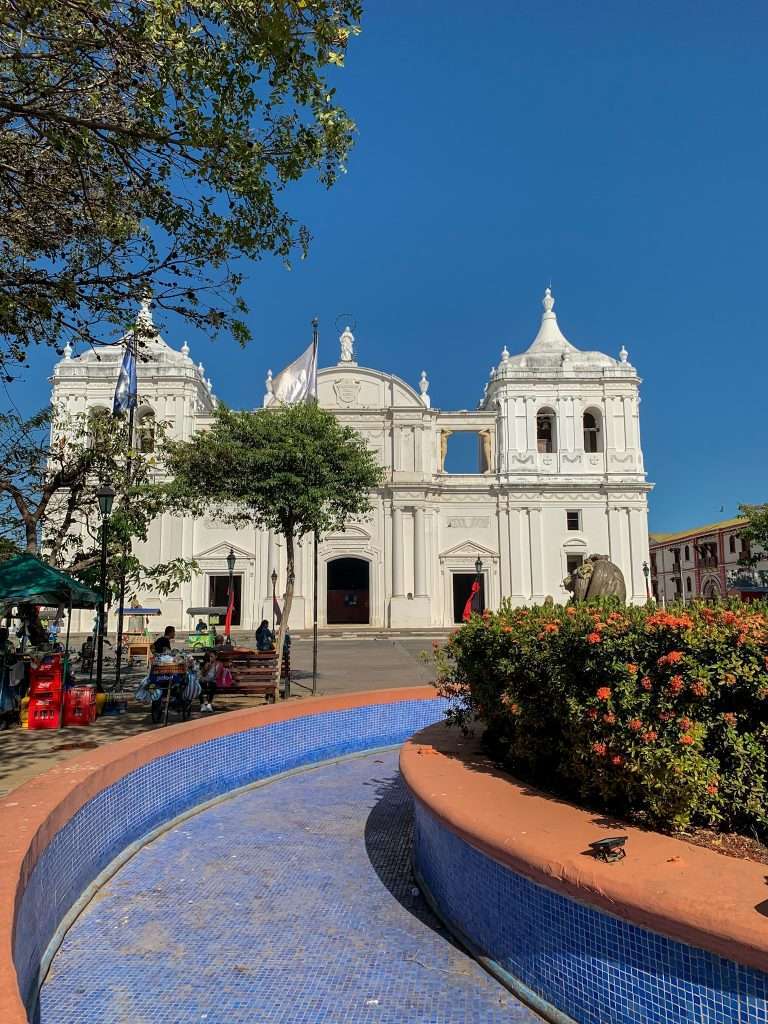 A view of Leon Cathedral in Nicaragua taken form the central square in the city. An empty fountain is partially visible in the foreground.