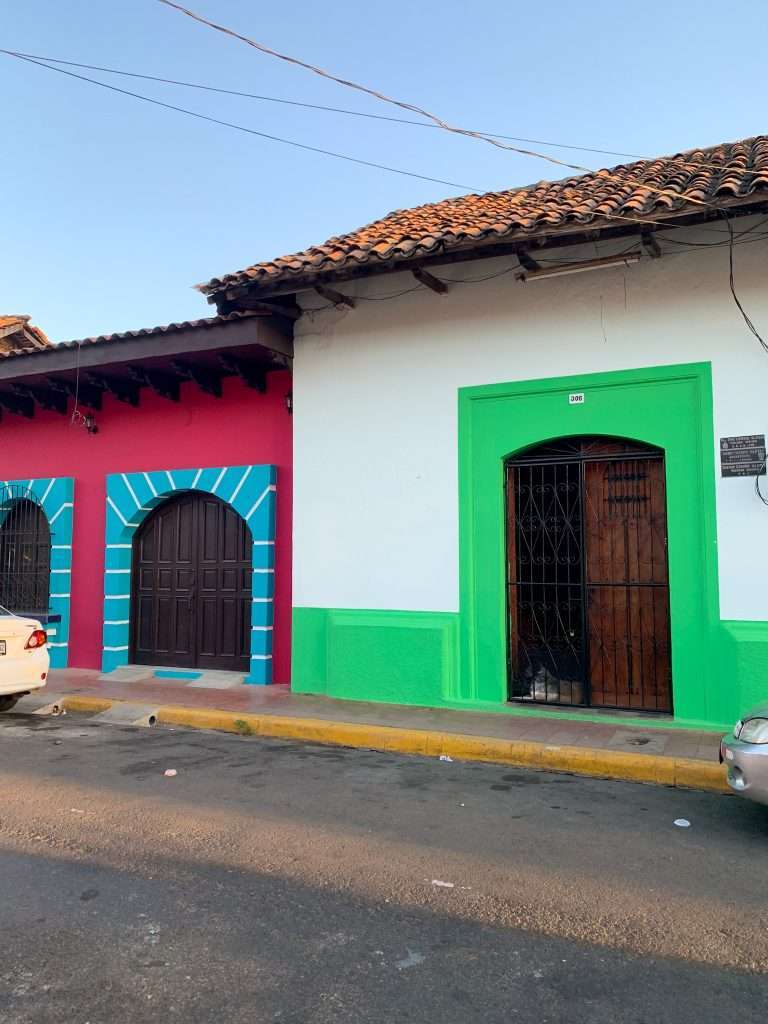 Another brightly coloured building sits on a road in Leon Nicaragua. Whites, greens, blues and reds are the dominate colours.