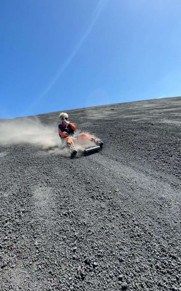 Image shows the author of this blog post sliding down the Cerro Negro active volcano in Nicaragua. Known as volcano boarding this is a must do activity when visiting the city of Leon.