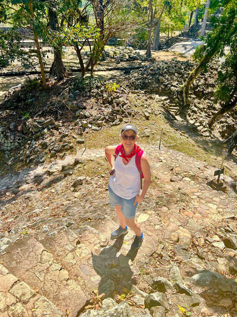 Image shows the author of this post standing on some stone steps and looking up at the camera at the Mayan Ruins of Copan, Honduras