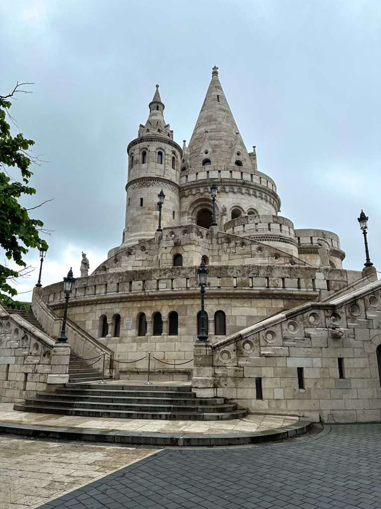 A view of part of Fisherman's Bastion in Budapest with several turret-like towers visible. A stairway leads up to different levels.