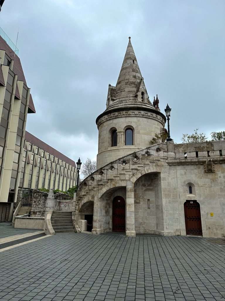 A view of part of Fisherman's Bastion in Budapest with a turret-like tower visible. A stairway leads up to different levels.