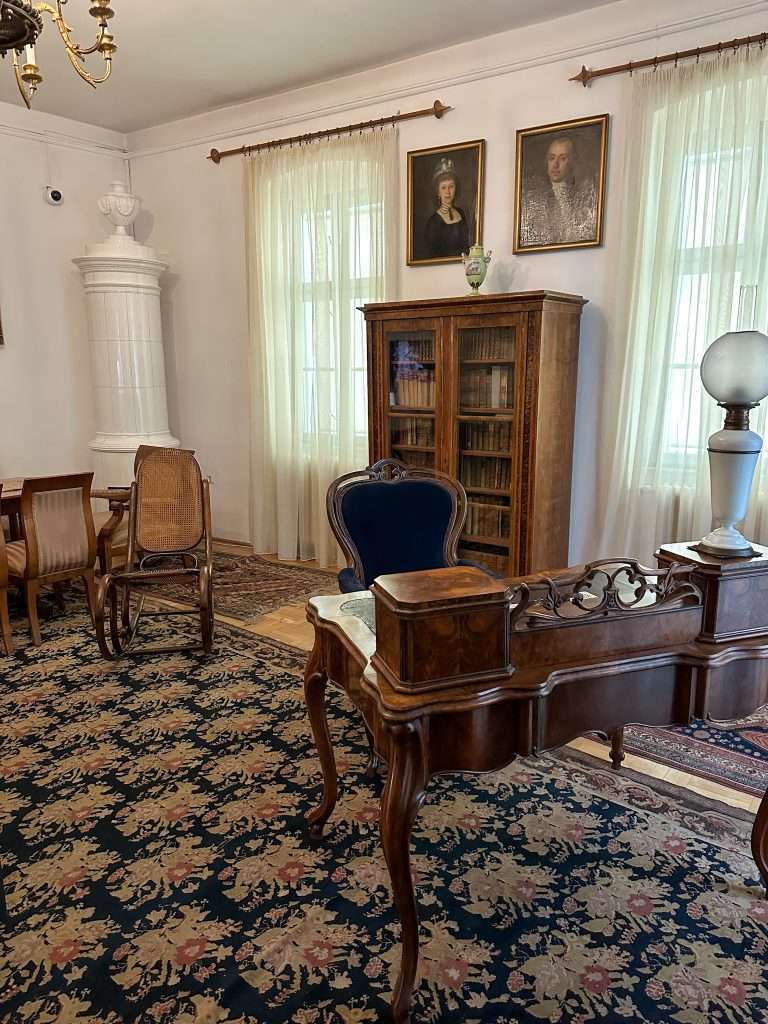 A view of Semmelweis' study in the Semmelweis museum with a wooden desk, a wooden bookcase with glass doors and two further chairs all placed on a rug.