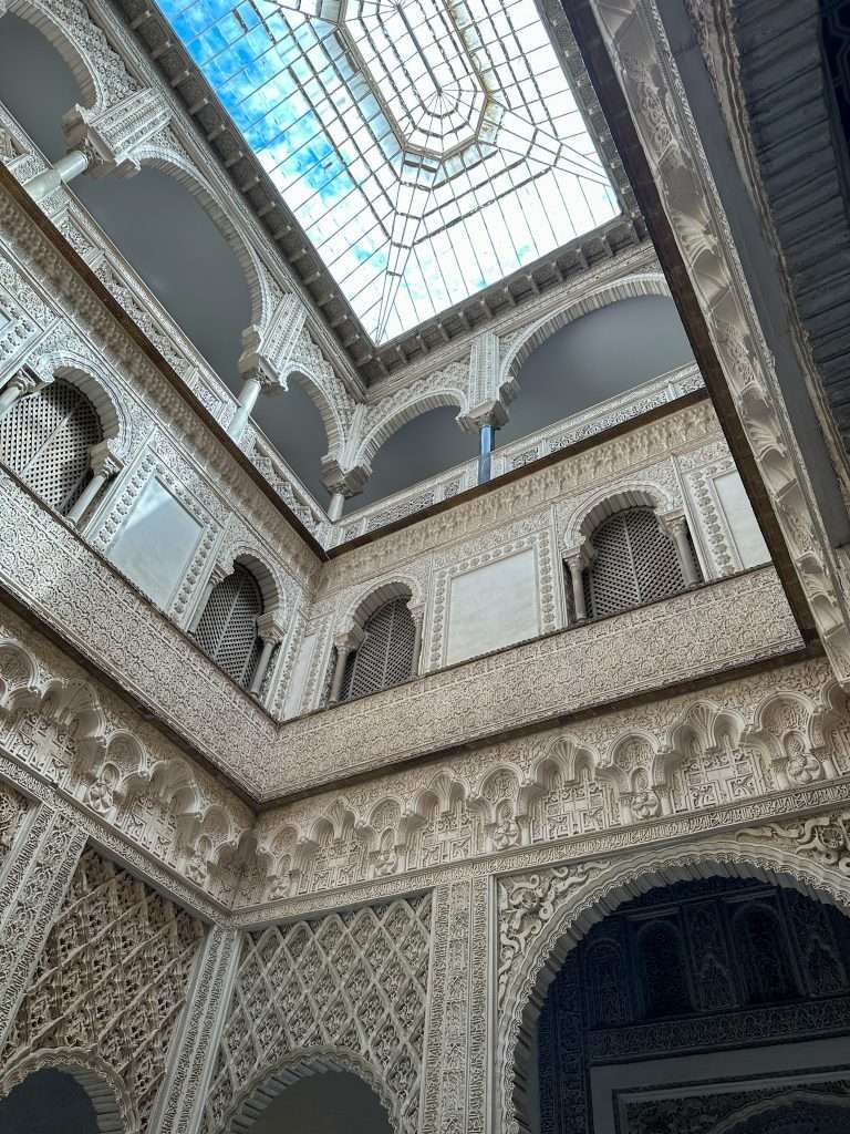 Image shows the inside of the beautiful Royal Alcázar showing the intricate lattice detailing. A visit to the Royal Alcázar is one of the best things to do in Seville.