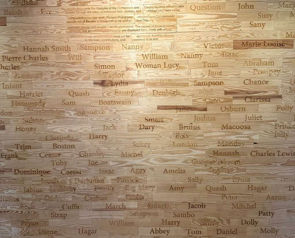 A wooden memorial wall which lists the names of the enslaved people within the Owens-Thomas House