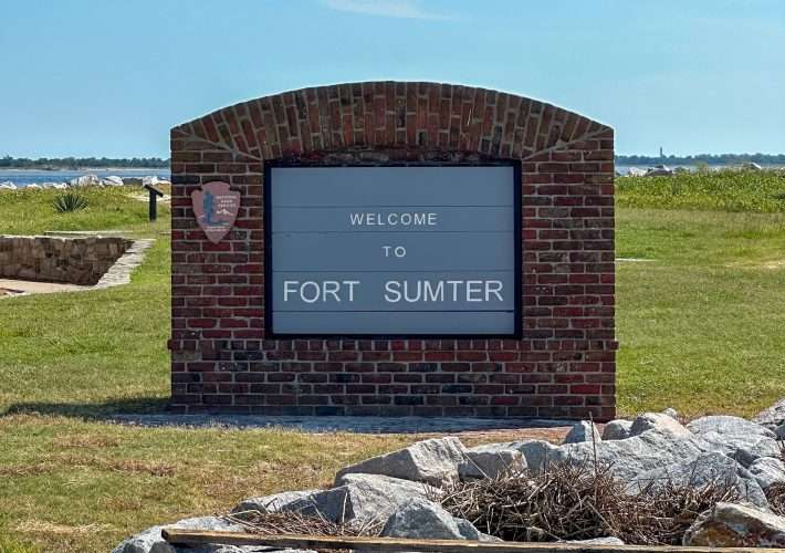A welcome to Fort Sumter sign made from red brick with the grey sign inlaid into the brick greets visitors to the Fort.
