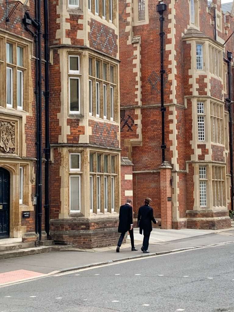 2 school boys are pictured walking away from the camera. Both are from the public school of Eton which can be seen on a day trip to Windsor.