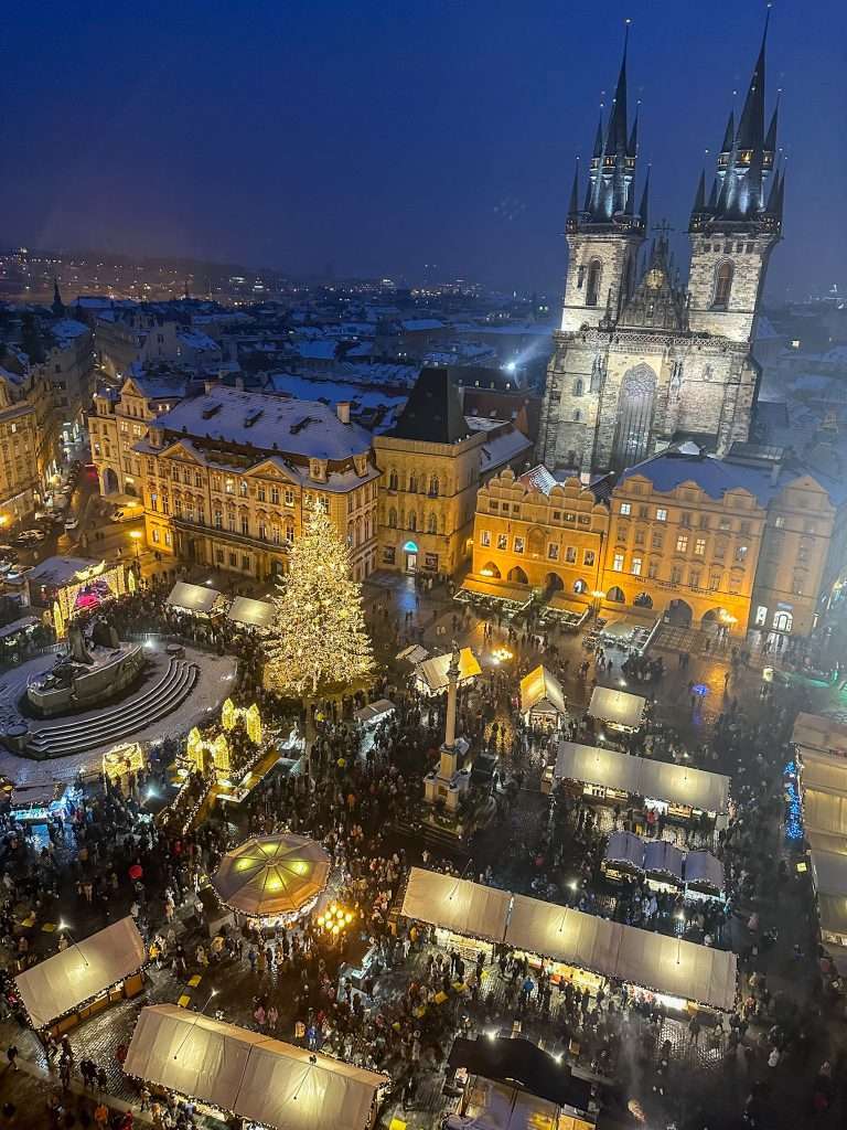 Image shows the Prague Christmas market taking place in the Old Town Square. The image is taken form the Town Hall tower which overlooks the Old town Square