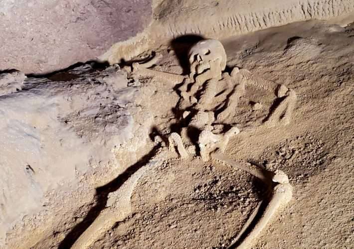 An ancient human skeleton lies amongst rocks inside the ATM cave