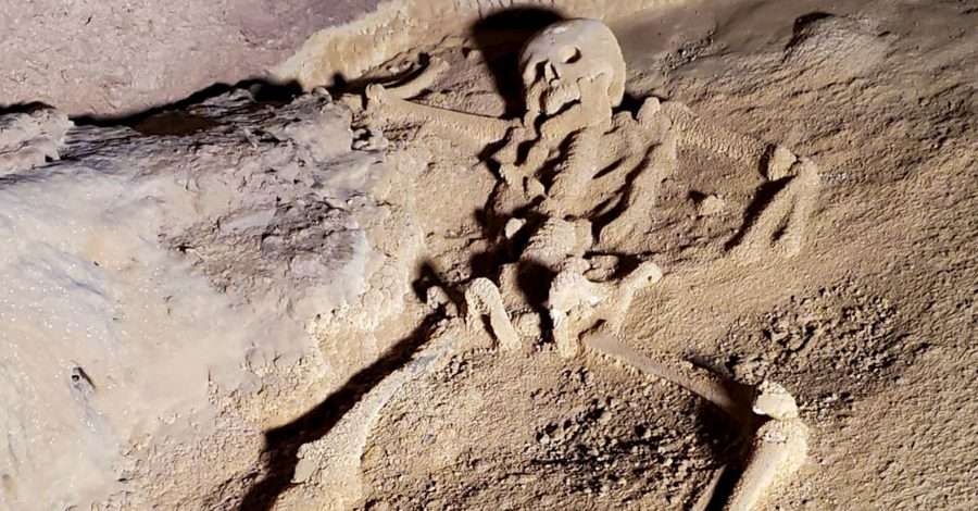 An ancient human skeleton lies amongst rocks inside the ATM cave