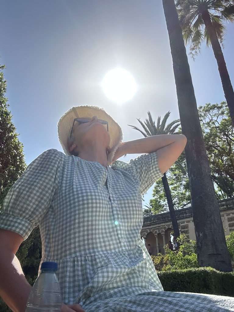 Image shows the author of this blog post sitting under the hot sun of Seville. This blog posts offers tips for coping with the heat of Seville. 