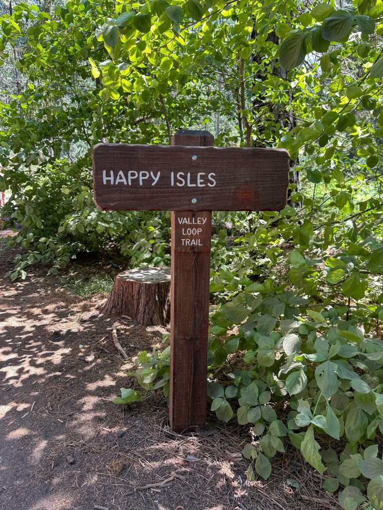 Image shows a sign reading "Happy Isles" from where hikes walk to the Mist Trail in Yosemite National park