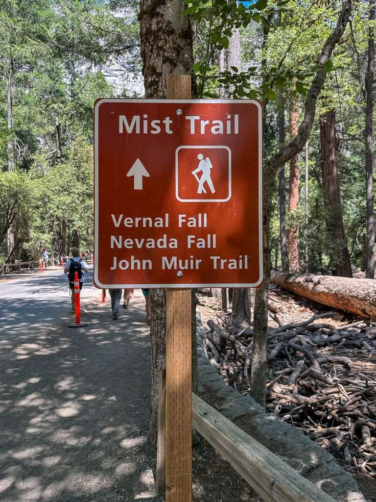 Image is of a sign in Yosemite National Park reading "Mist Trail" with an arrow pointing toward the trail and reference to Vernal Fall, Nevada Fall and the John Muir Trail.