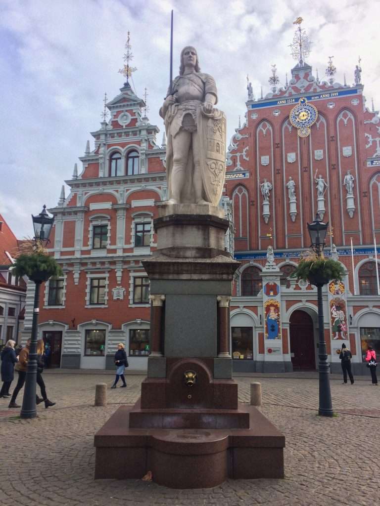 Image shows a statute of St Roland located in Town Hall Square in Riga. In the background is the ornate House of he Black Heads. 
