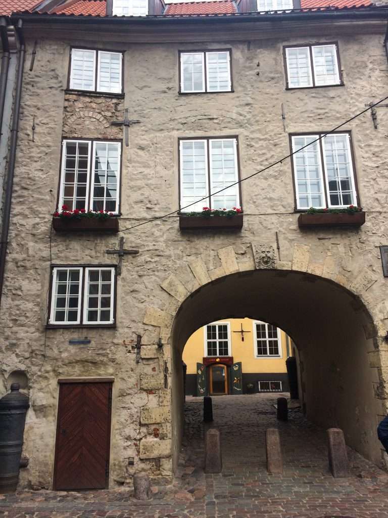 Image shows the Swedish Gate located in Riga Old Town. 7 windows are visible in the image as is the arch forming the gateway.
