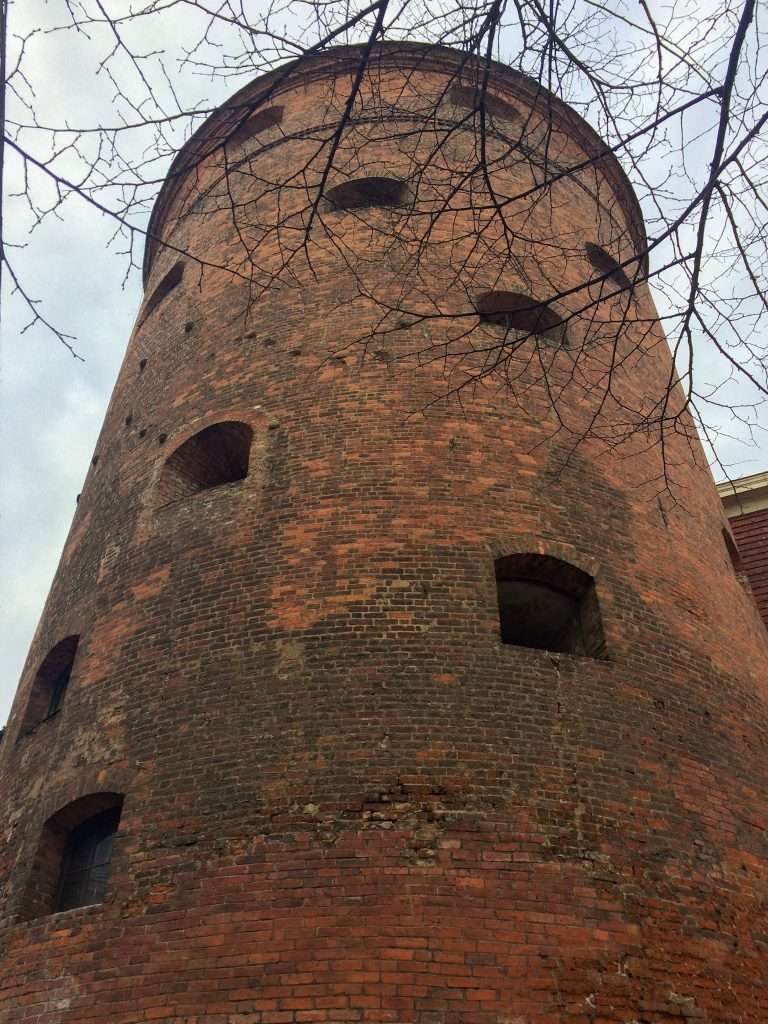 Image shows a close up of Riga's Powder Tower, a red brick, turret shaped tower with multiple windows visible.