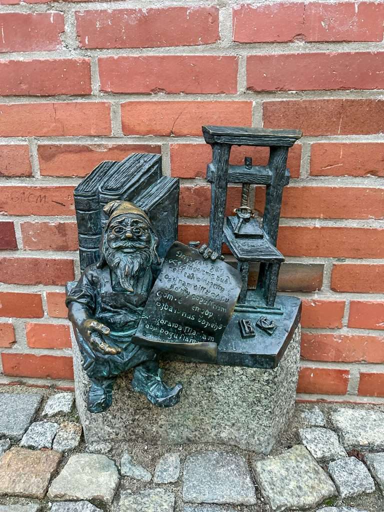 Image shows a dwarf statue in Wroclaw called the Printer.