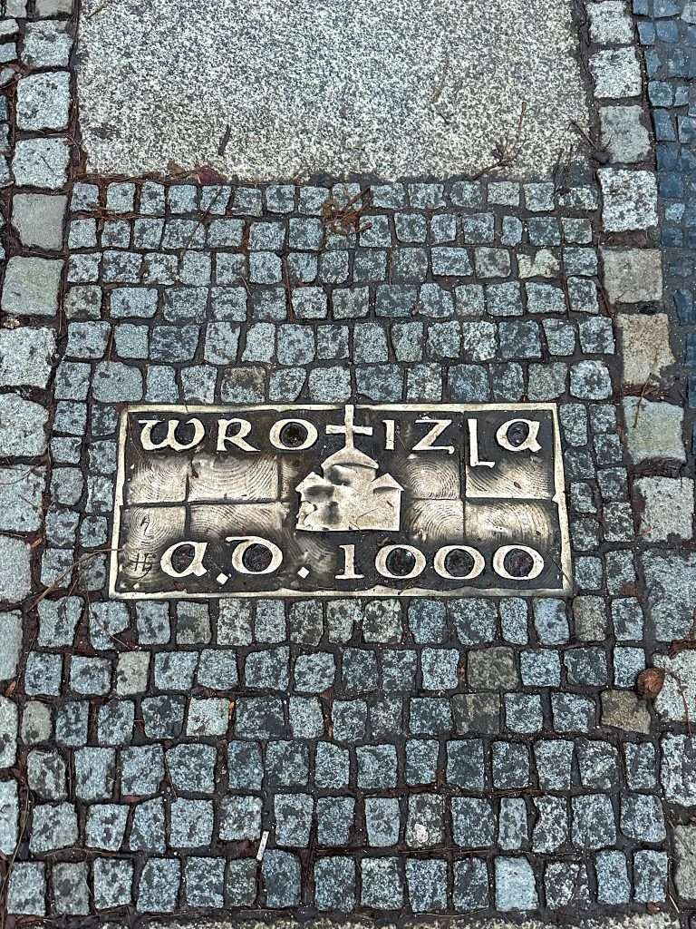 Image shows a bronze plate embedded in the pavement in Wroclaw Poland commemorating the year 1000 when the city was founded and known as Wrotizla.