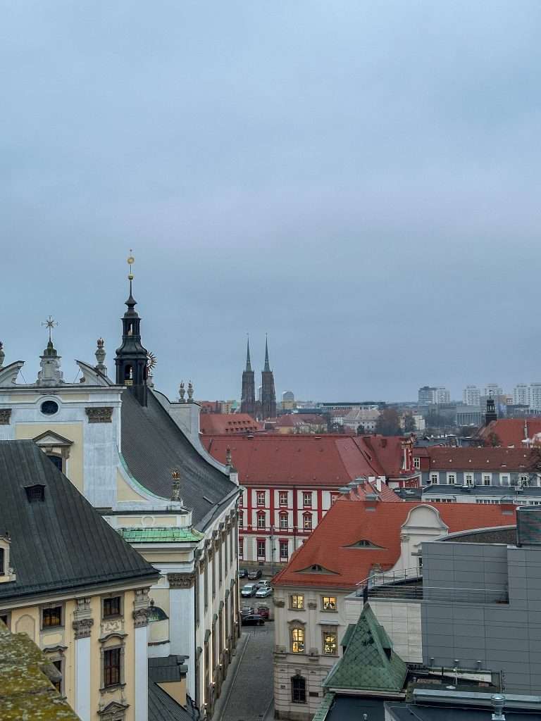 Image shows the view over Wroclaw from the top of the Mathematical Tower within Wroclaw University. The towers of the Cathedral of St John the Baptist can be seen in the distance.