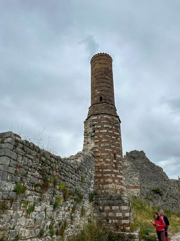 Red and white brick minaret which formed part of the Red Mosque within Berat Castle is the most prominent of the mosque remains. Parts of the old walls are visible as are some grasses growing through the old walls.