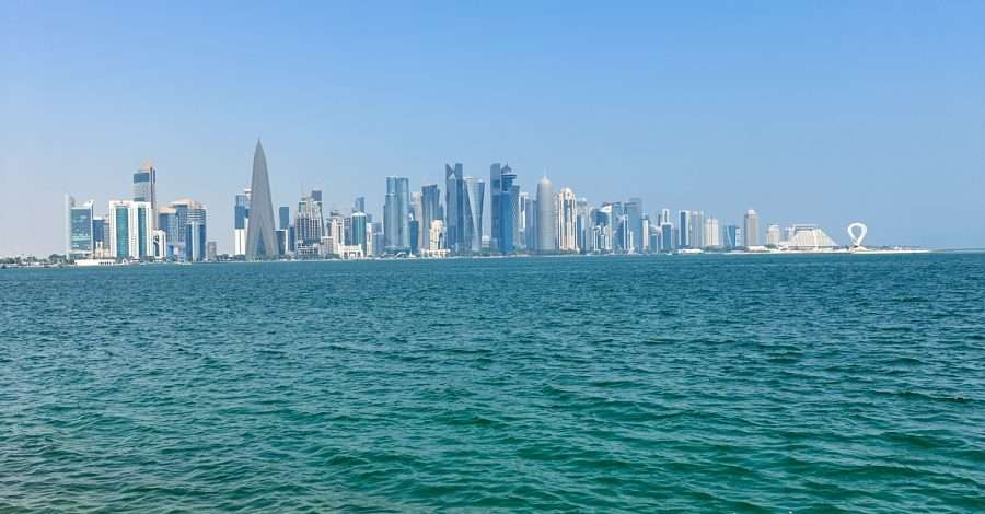 The Doha skyline looking across the sea. Various tall buildings are visible, including one that is a tall pyramid like shape.