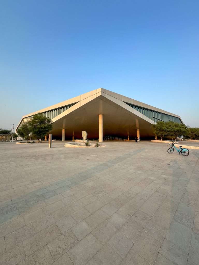 External view of the diamond shaped national Library of Qatar. An electric bicycle is visible on the right hand side although no rider is to be seen.